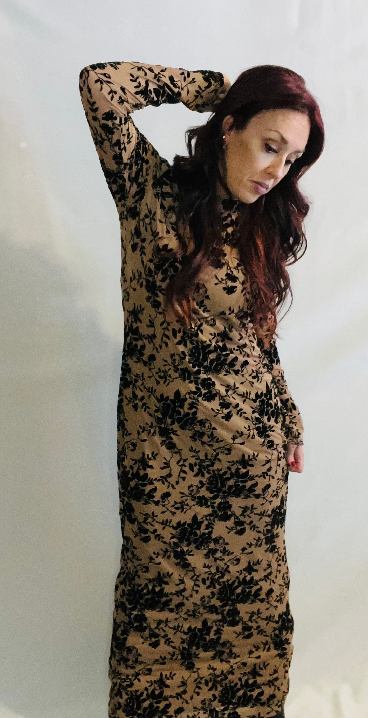 Woman wearing a long, floral-patterned dress against a white background