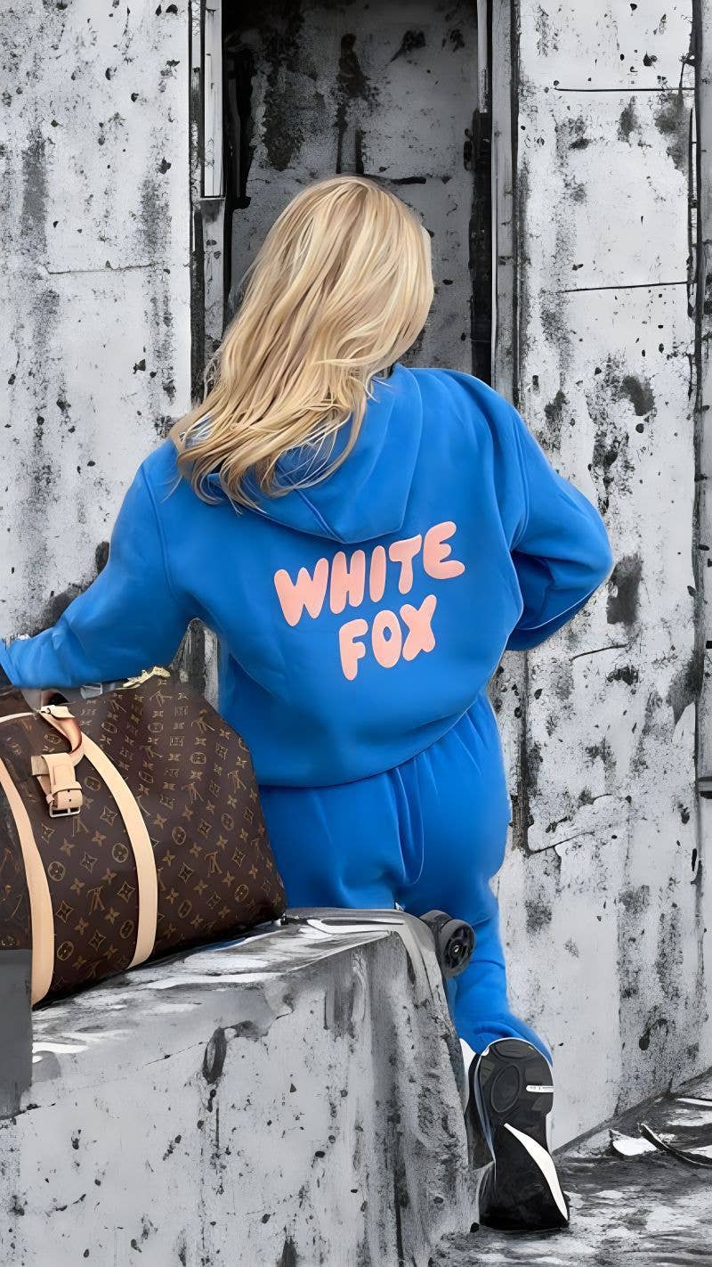 Person wearing a blue tracksuit with 'White Fox' text, standing against a textured wall.