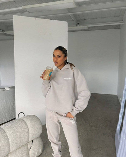 Person wearing a gray sweatshirt and pants in a minimalistic room.