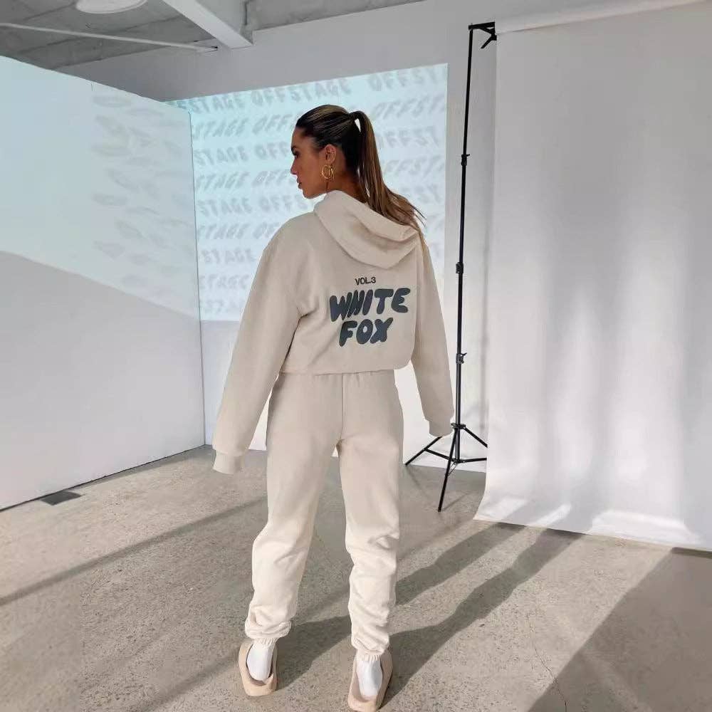 Person wearing a beige tracksuit with 'White Fox' branding in a studio setting.
