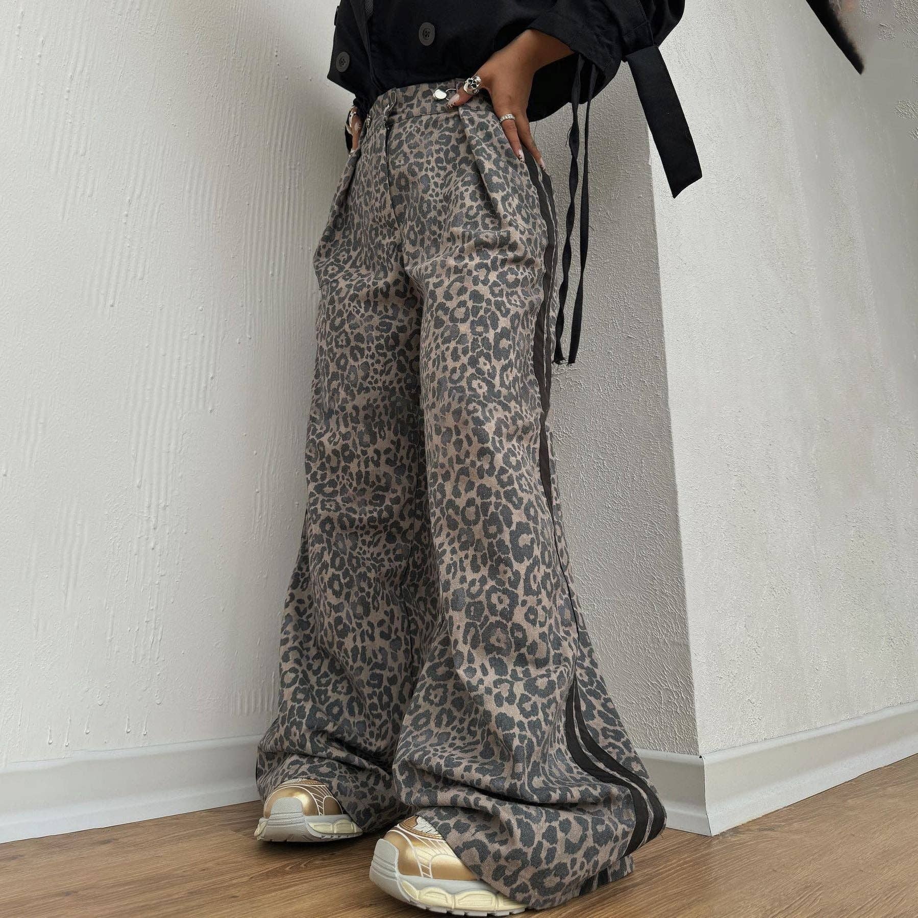 Person wearing leopard print pants against a plain wall.