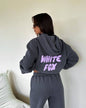 Person wearing a gray hoodie with 'White Fox' text on the back, standing against a white wall.