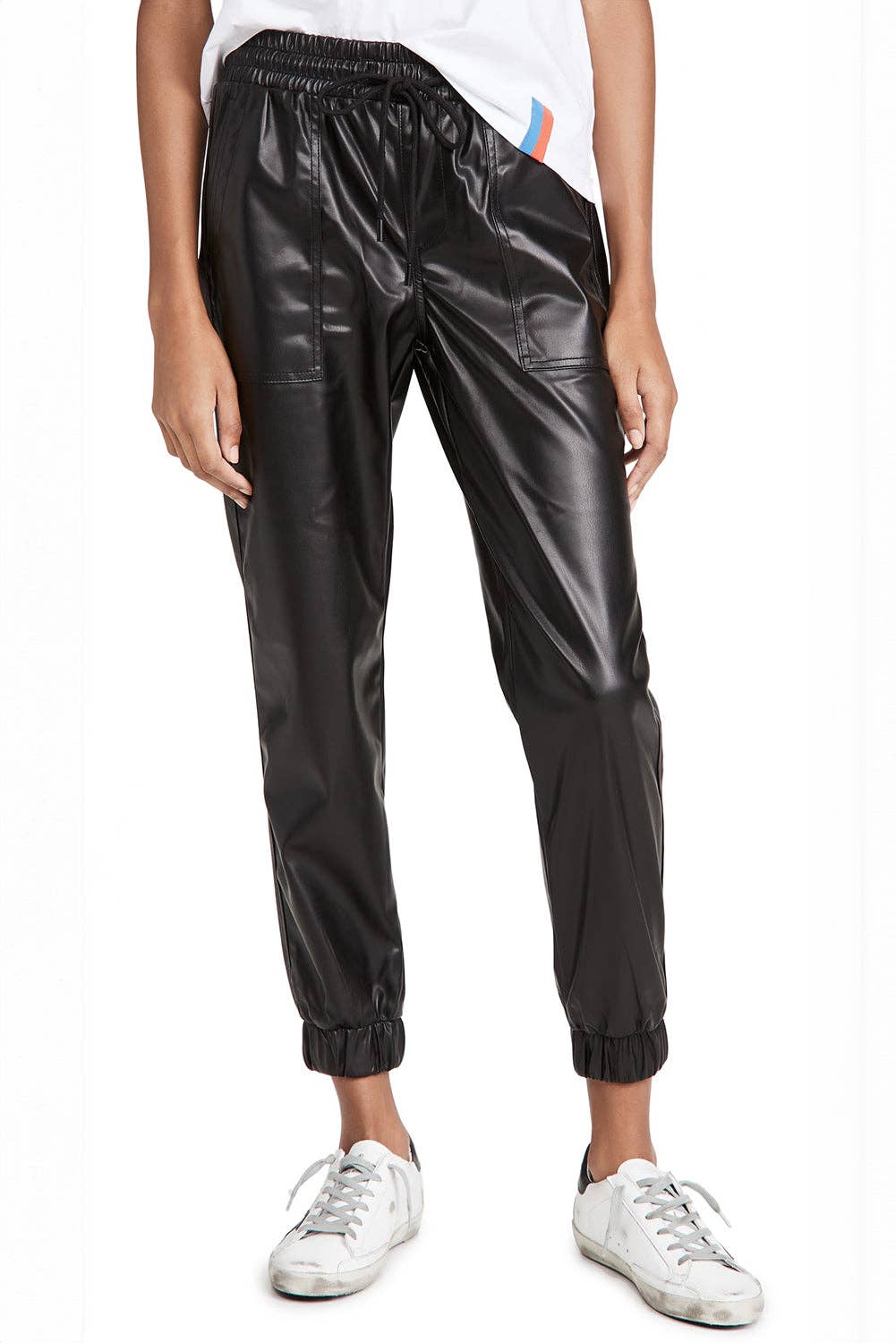 Person wearing black shiny pants and white sneakers on a white background