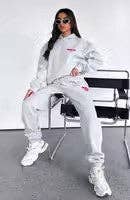 Person wearing a white tracksuit with red accents sitting on a chair.