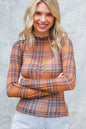 Woman wearing a plaid shirt with sheer panels against a gray background