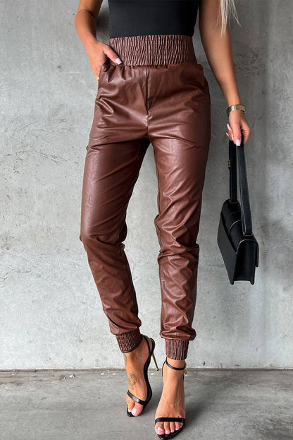 Person wearing brown leather jogger pants against a gray wall.