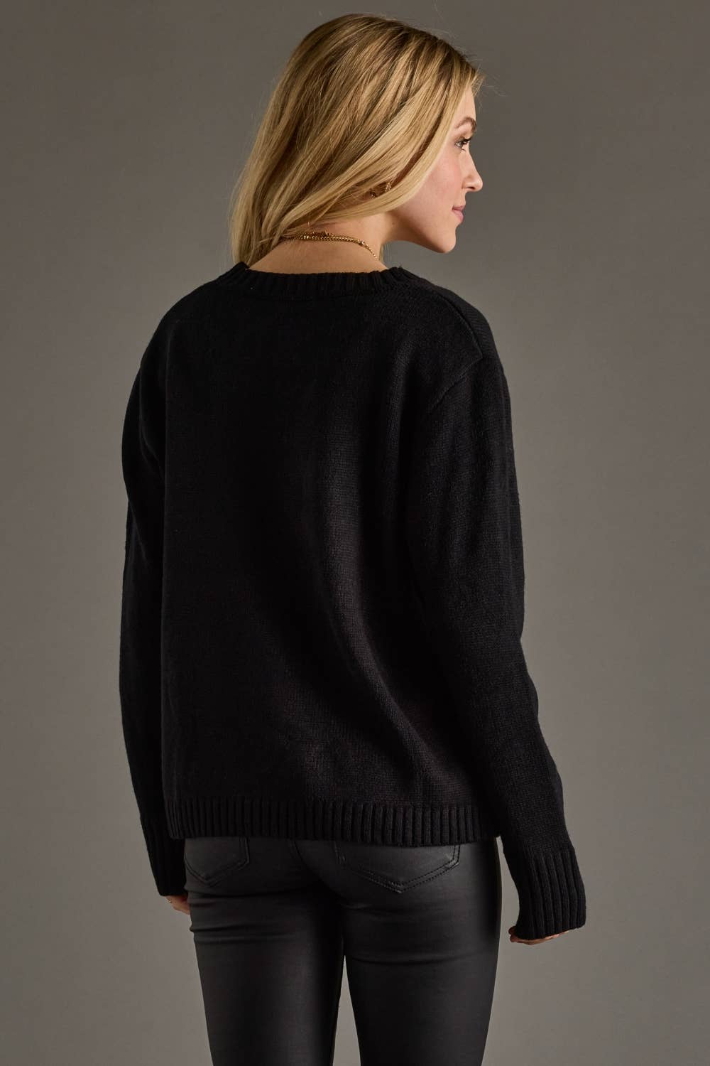 Woman wearing a black sweater against a gray background
