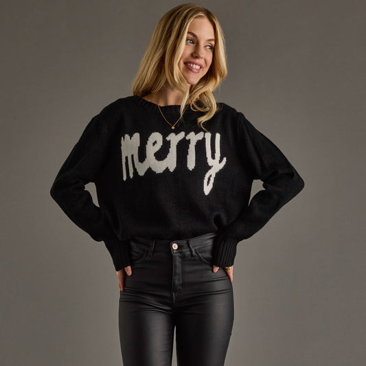 Woman wearing a black sweater with 'merry' text on a gray background