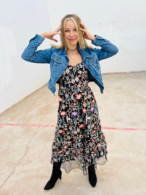 Woman wearing a floral dress with a denim jacket in an indoor setting