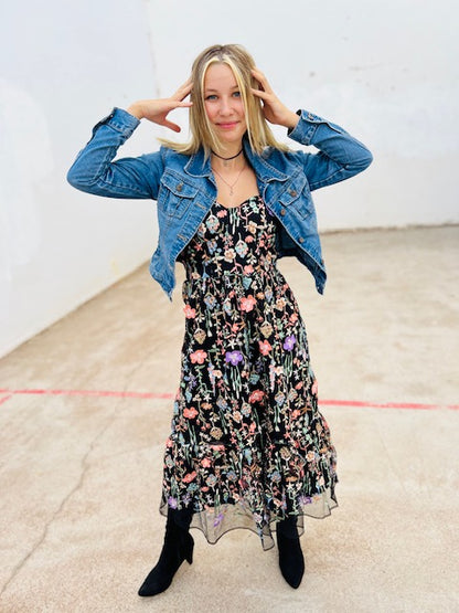 Woman wearing a floral dress with a denim jacket in an indoor setting