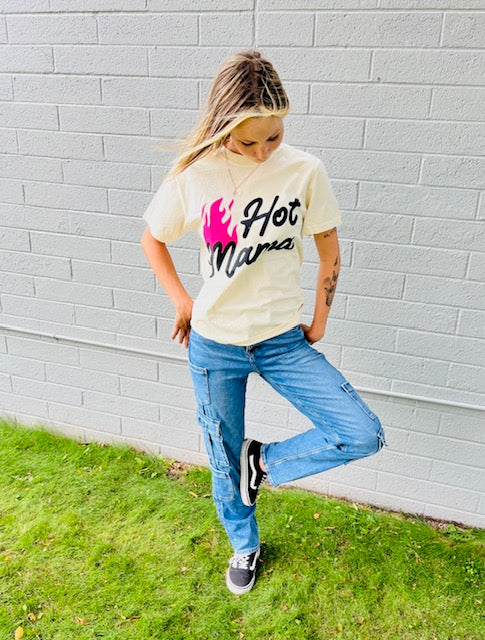 Person wearing a 'Hot Mama' t-shirt against a gray brick wall.