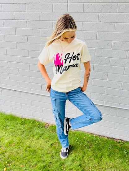 Person wearing a 'Hot Mama' t-shirt against a gray brick wall.