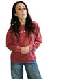 woman in crimson sweater and jeans in front off white background