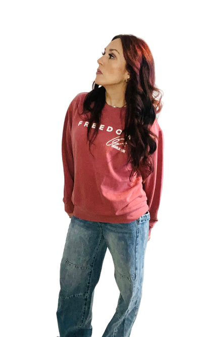 woman in crimson sweater and jeans in front off white background