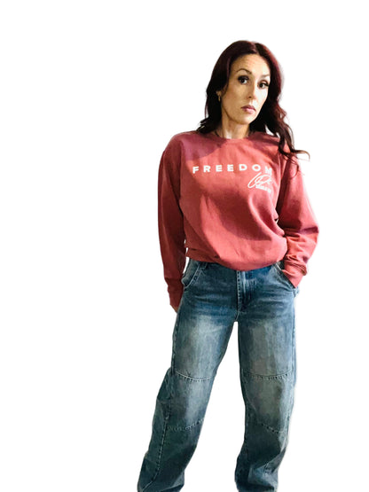 woman in crimson sweater and jeans in front off white background