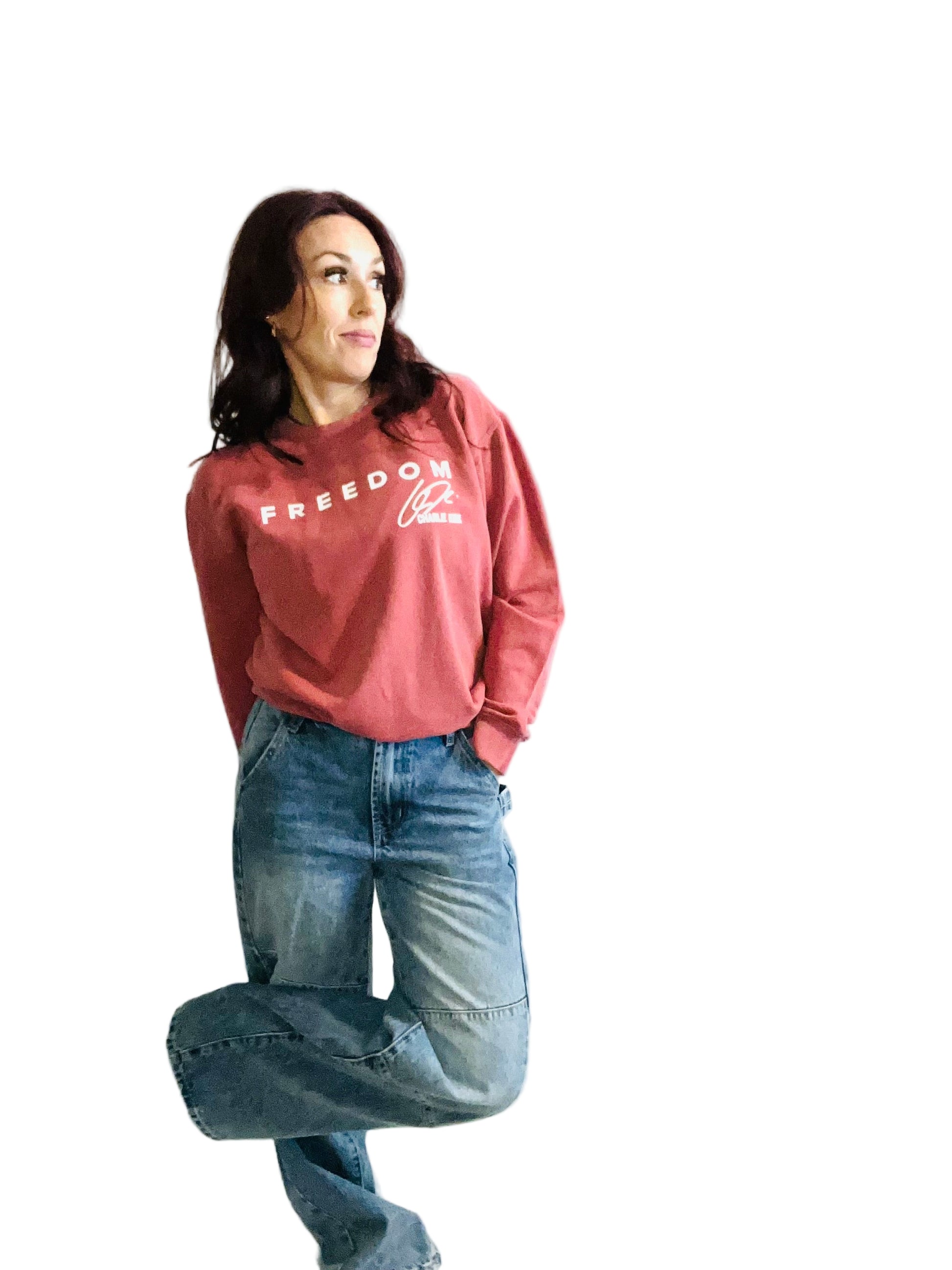 woman in crimson sweater and jeans in front off white background