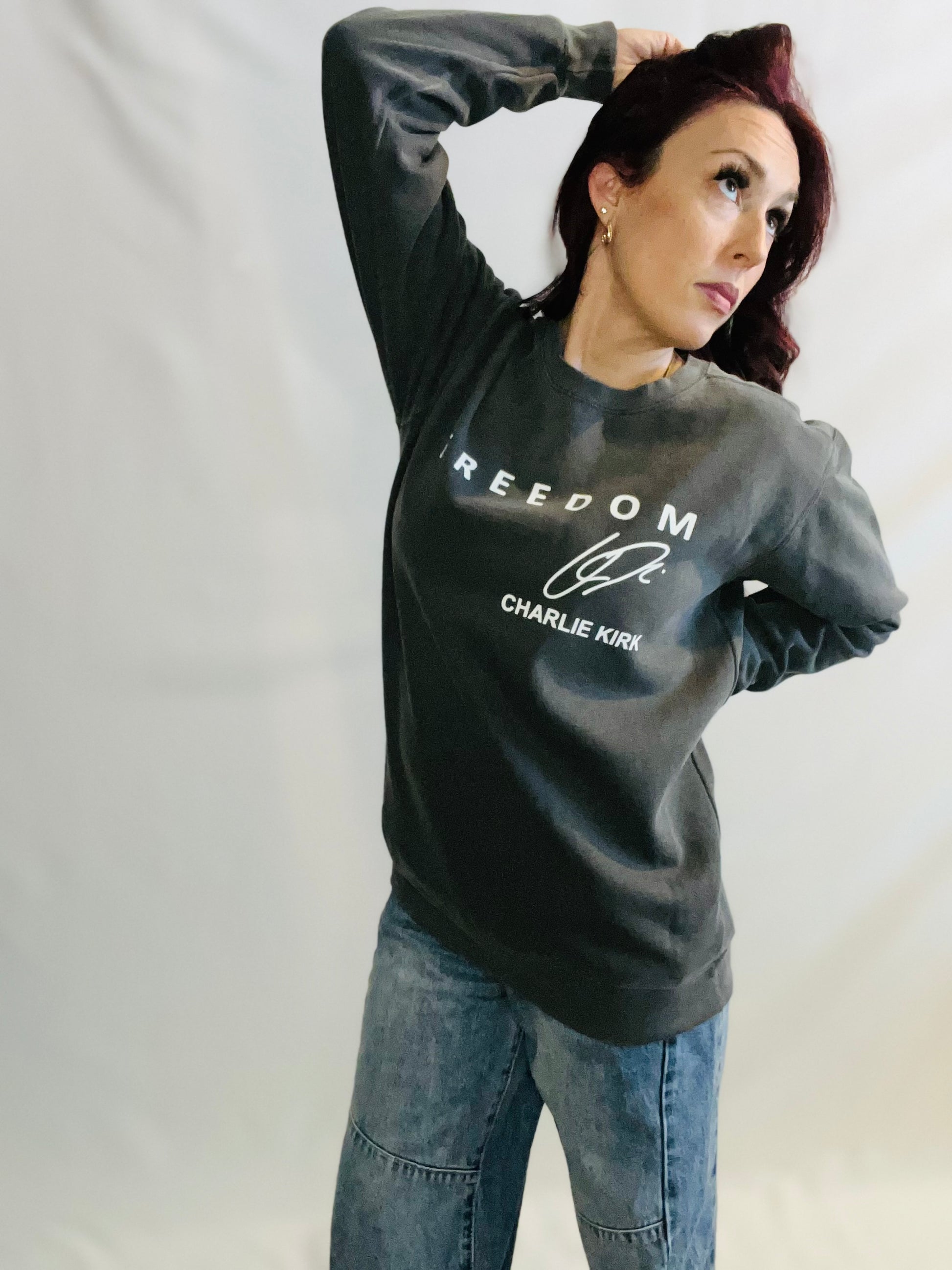 woman in pepper grey sweater that says freedom and jeans in front of white background