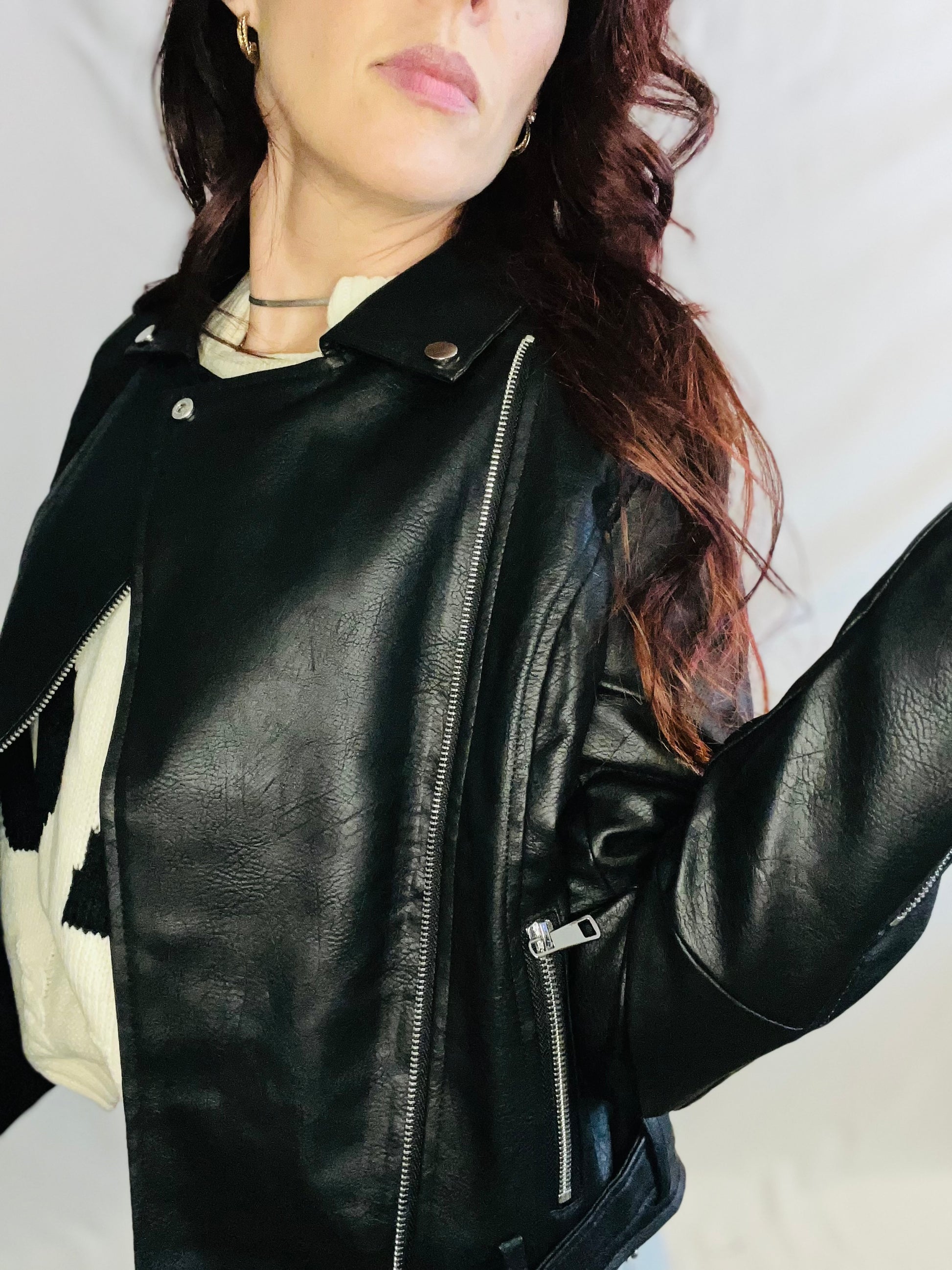 Person wearing a black leather jacket against a neutral background