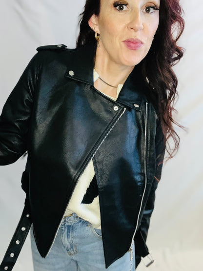 Person wearing a black leather jacket with a plain background