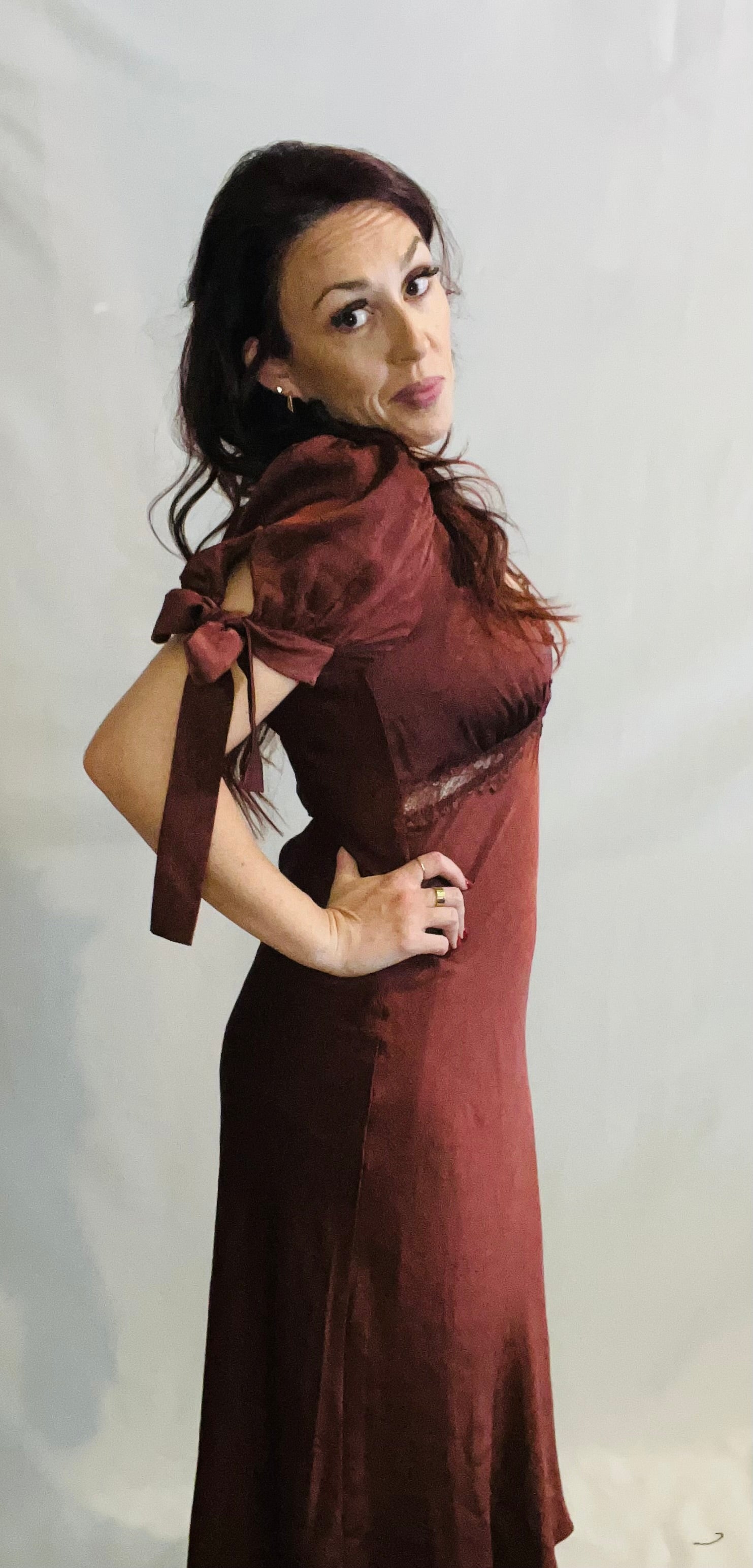 Woman wearing a burgundy dress with a matching scarf against a plain background