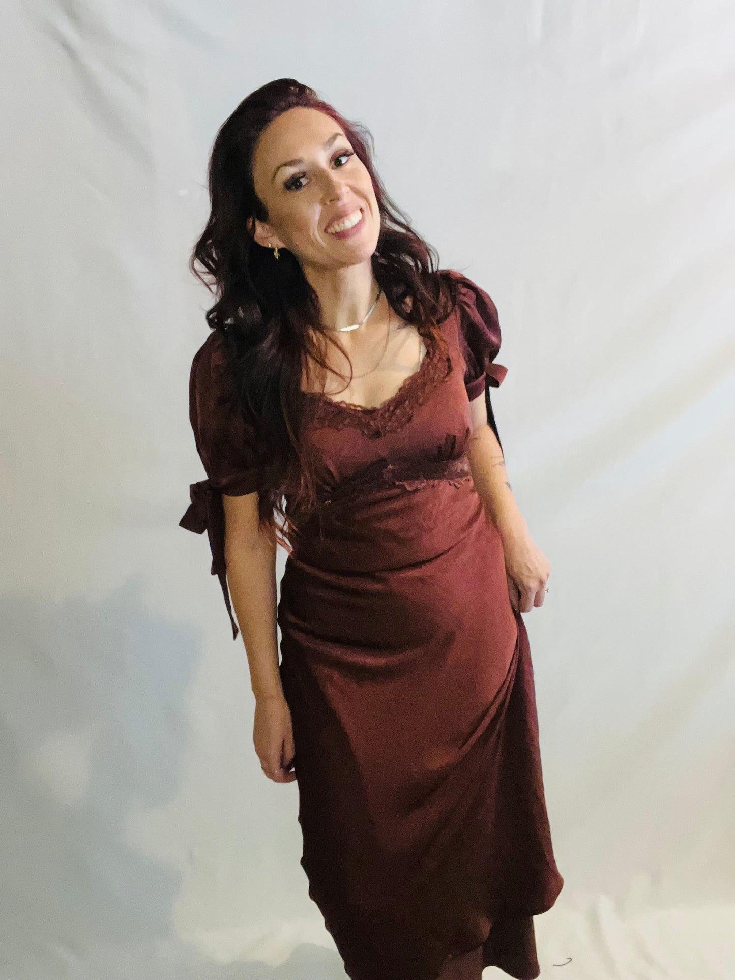 Woman wearing a burgundy dress with puffed sleeves against a plain background