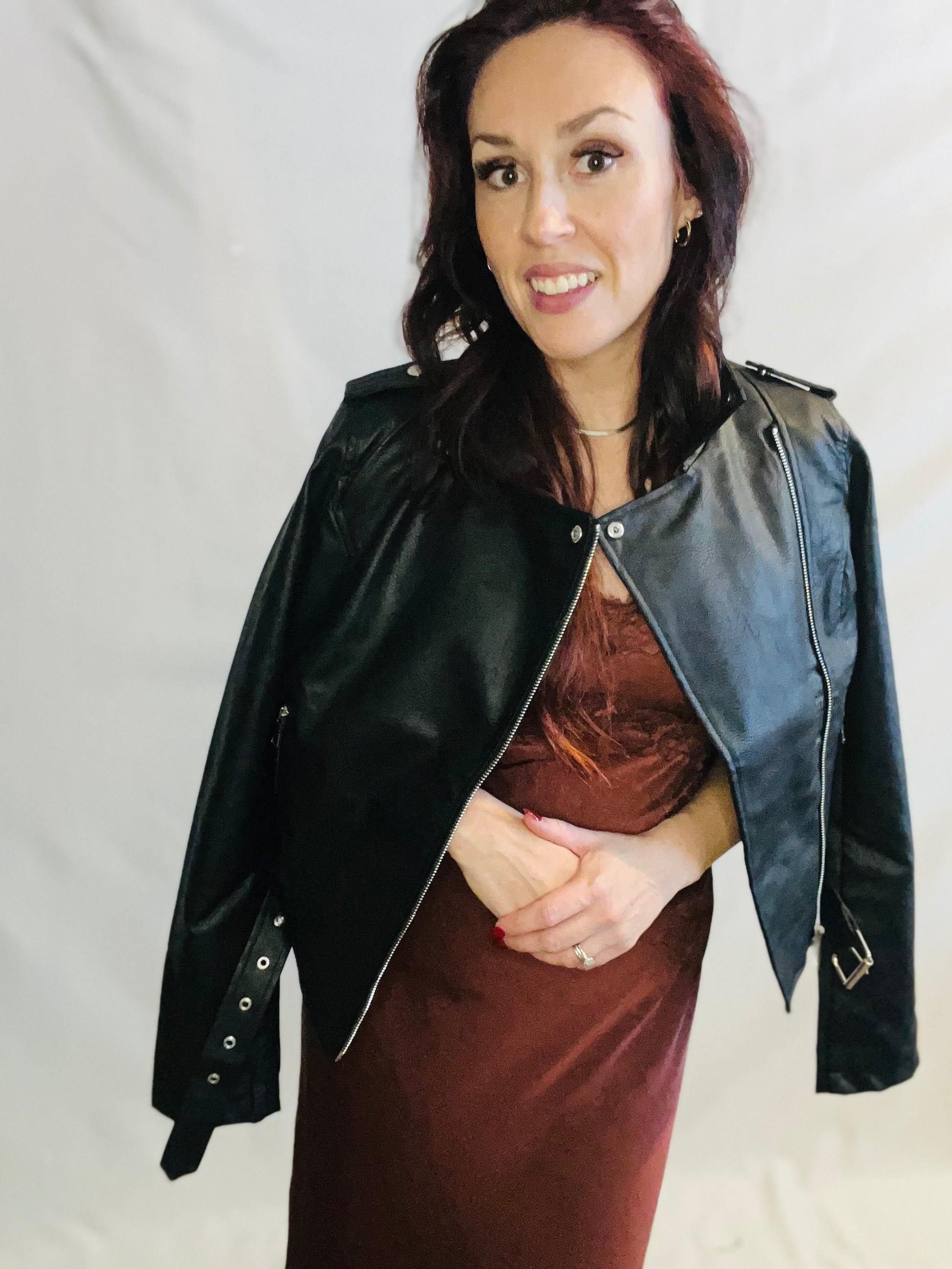 Woman wearing a black leather jacket with a gray shoulder panel on a plain background