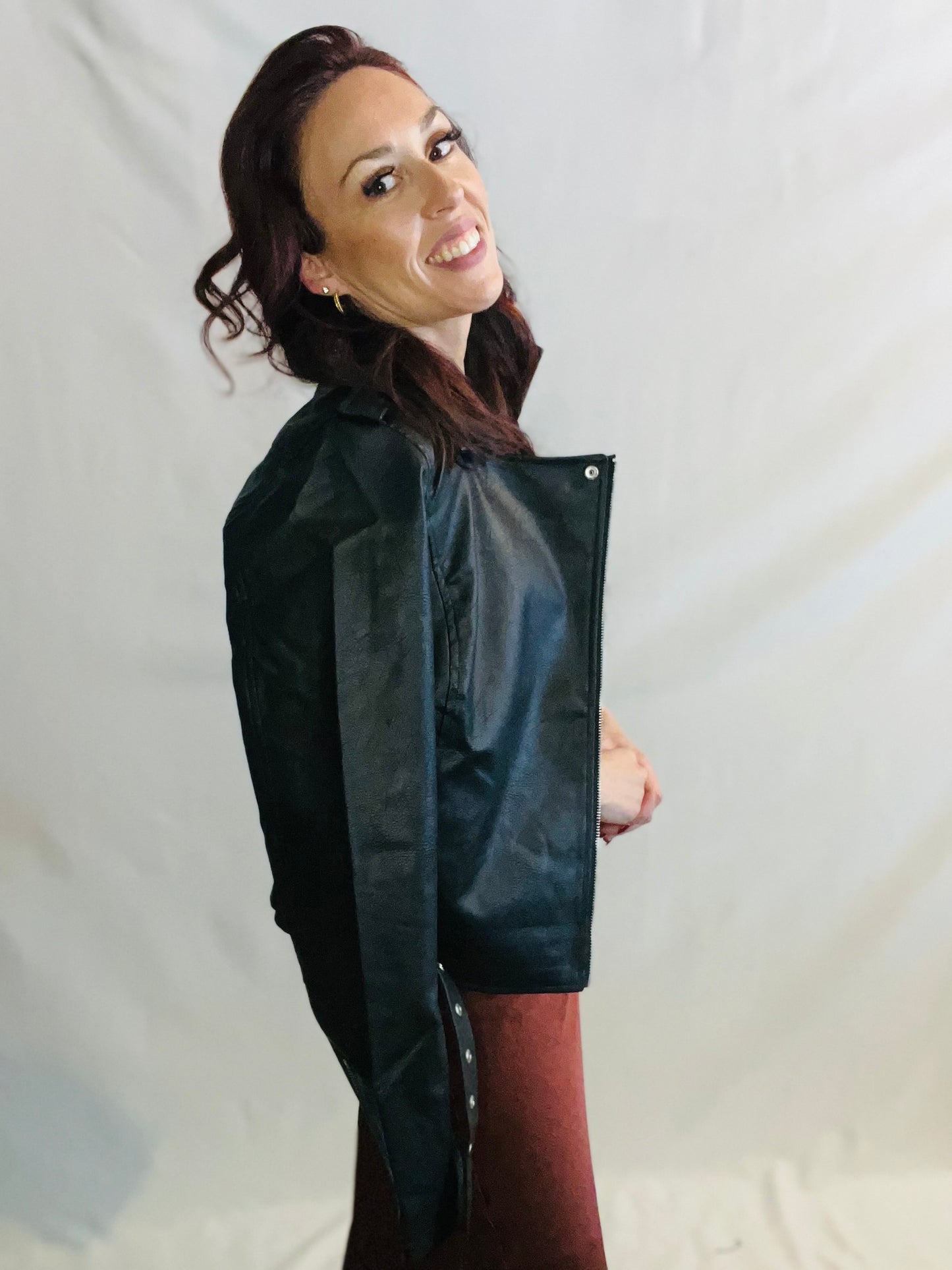 Woman wearing a black raincoat against a plain background