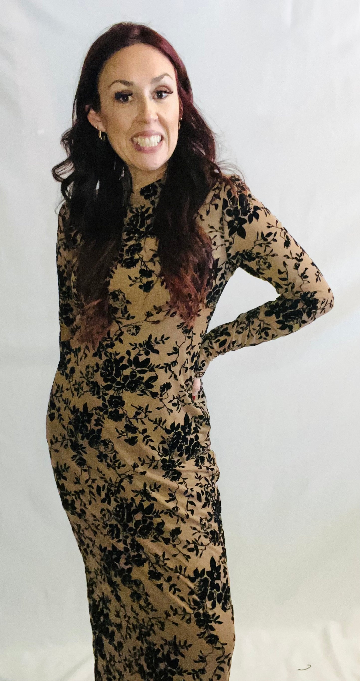 Woman wearing a long-sleeve dress with black floral pattern on a white background