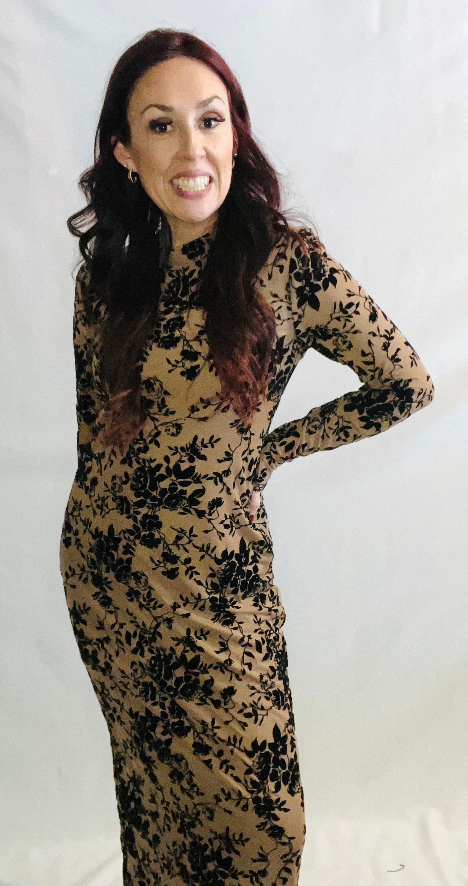 Woman wearing a long-sleeve dress with black floral pattern on a white background