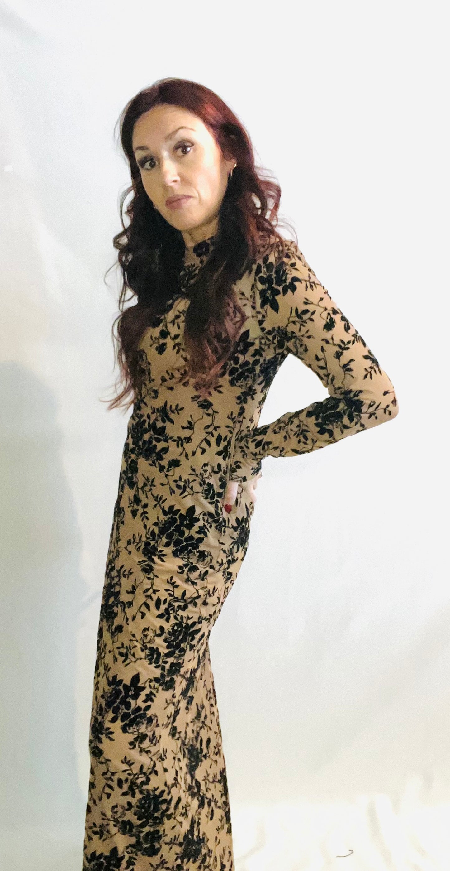 Woman wearing a long, floral-patterned dress against a white background