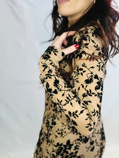 Beige dress with black floral pattern worn by a person against a neutral background
