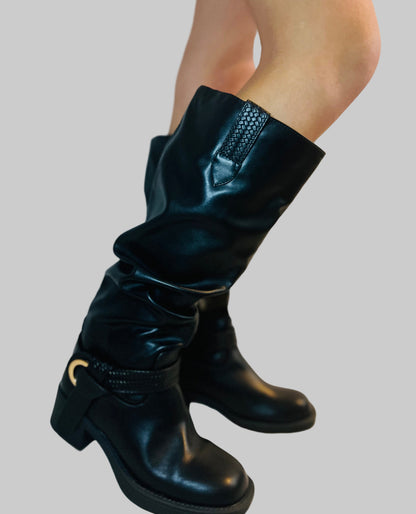 Black knee-high boots worn by a person on a light background