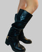 Black knee-high boots worn by a person on a light background