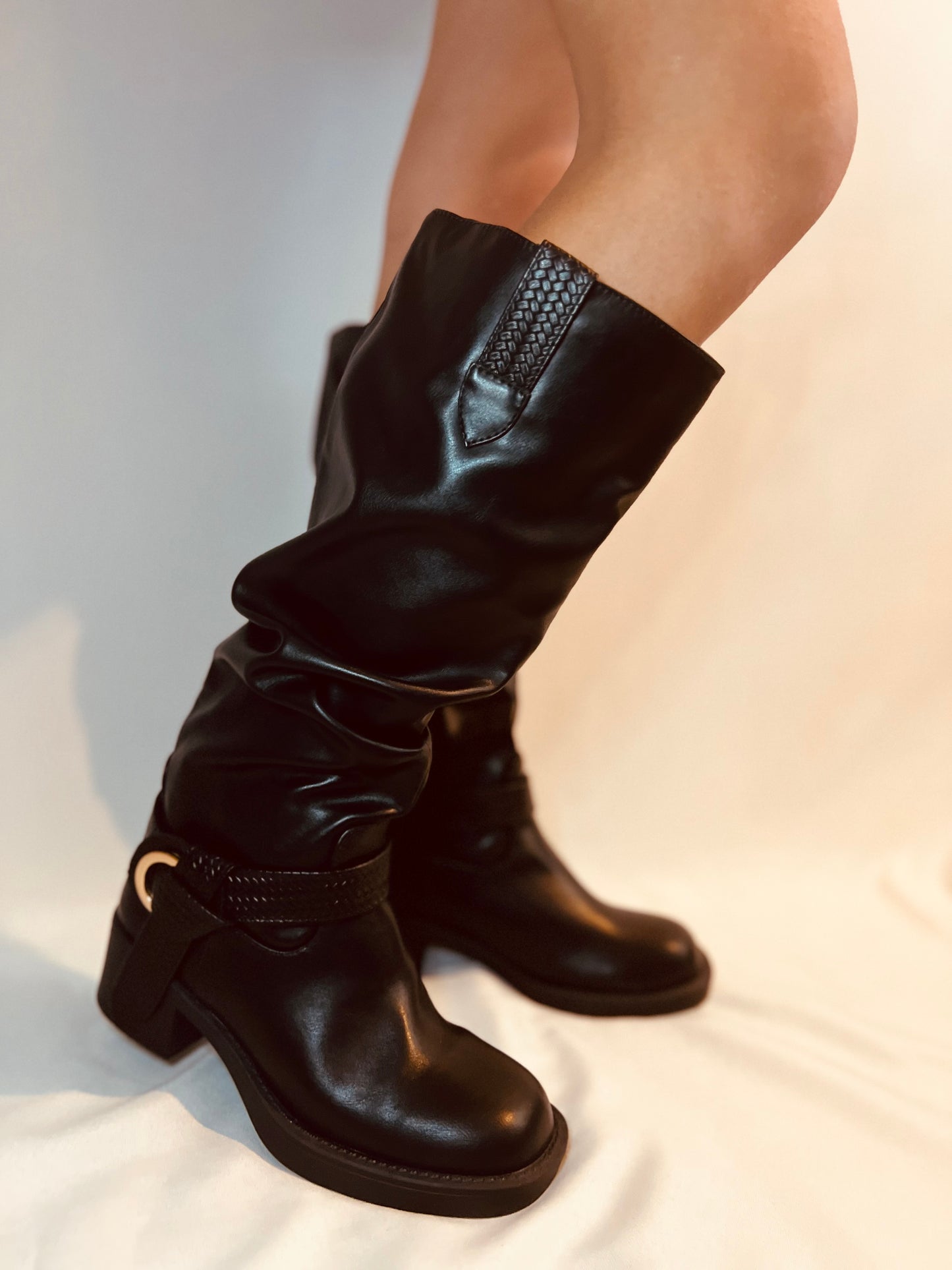 Black leather boots worn by a person on a light background