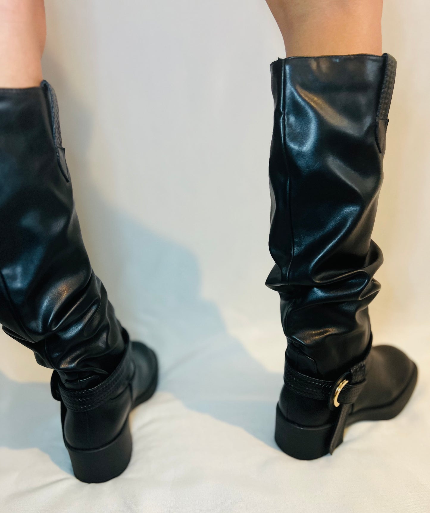 Black knee-high boots on a light gray background