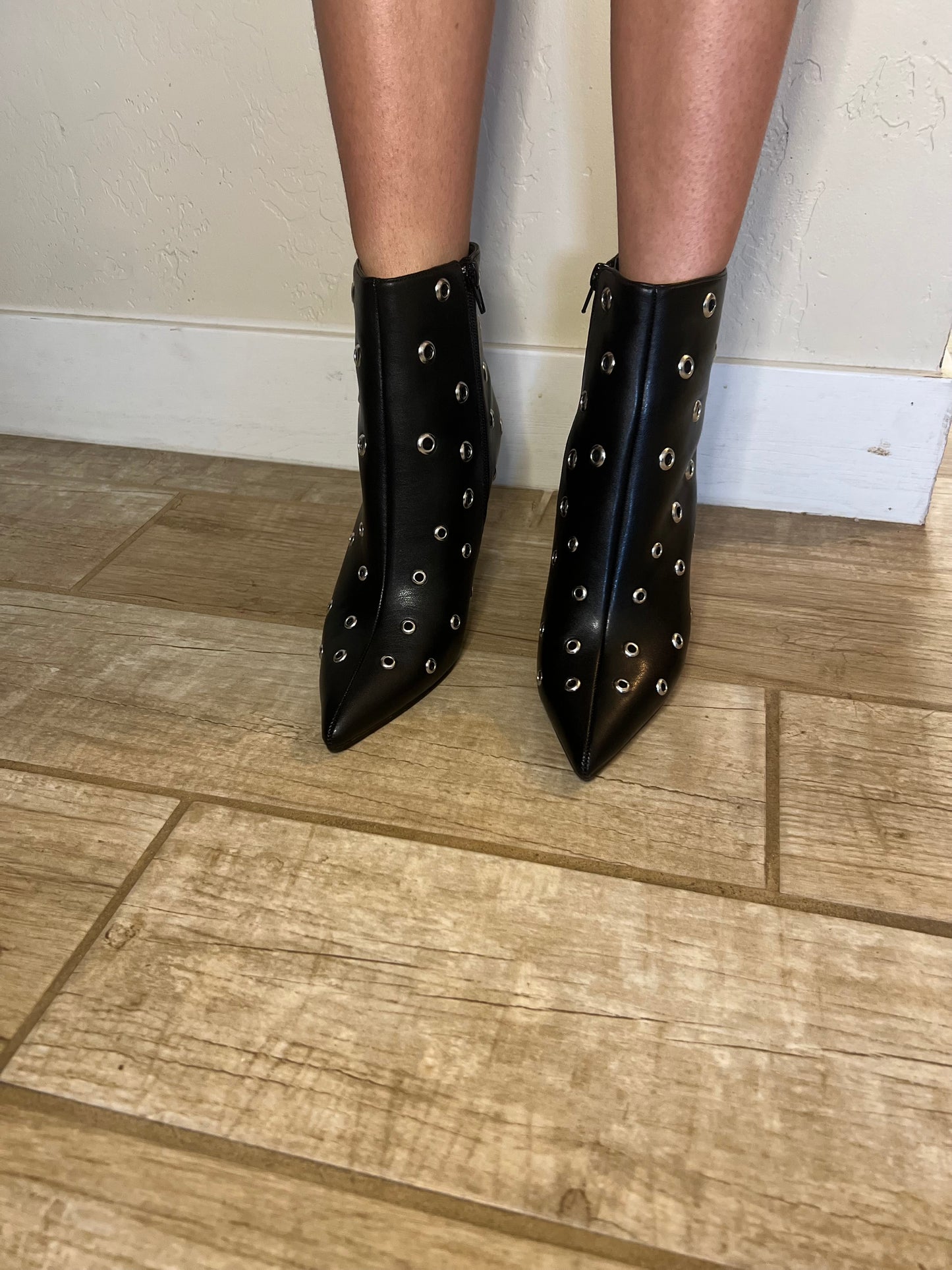 Black studded ankle boots on a wooden floor