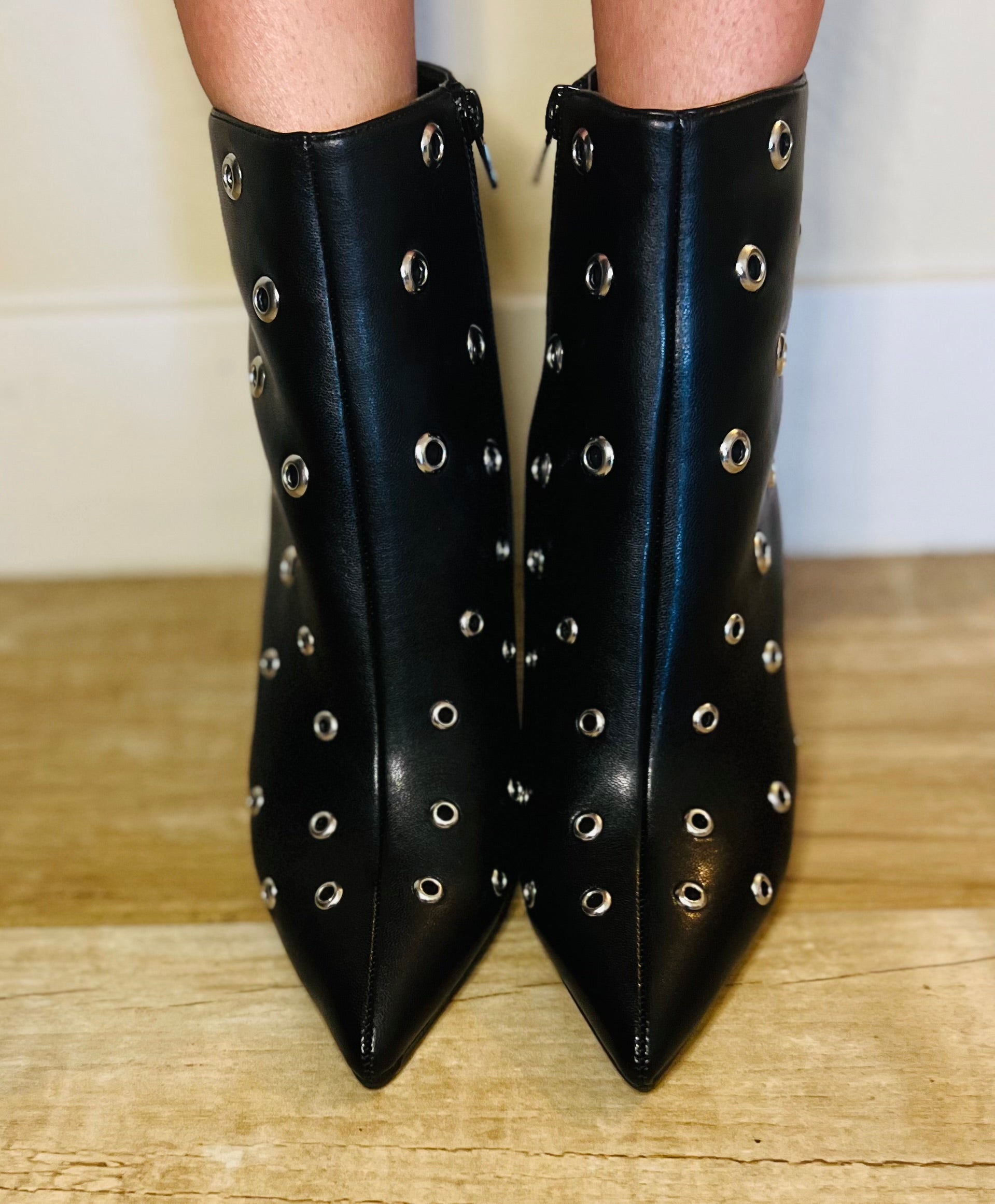 Black studded ankle boots on a wooden floor