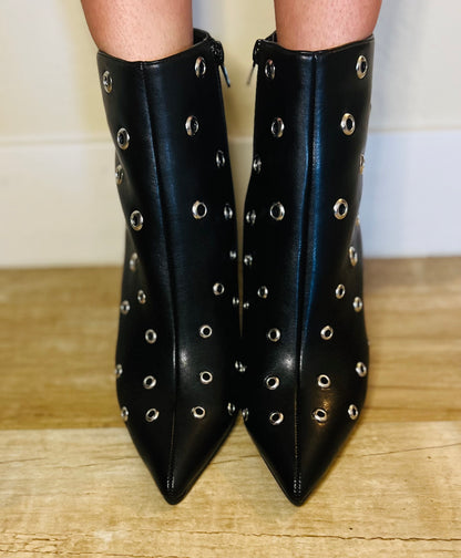 Black studded ankle boots on a wooden floor