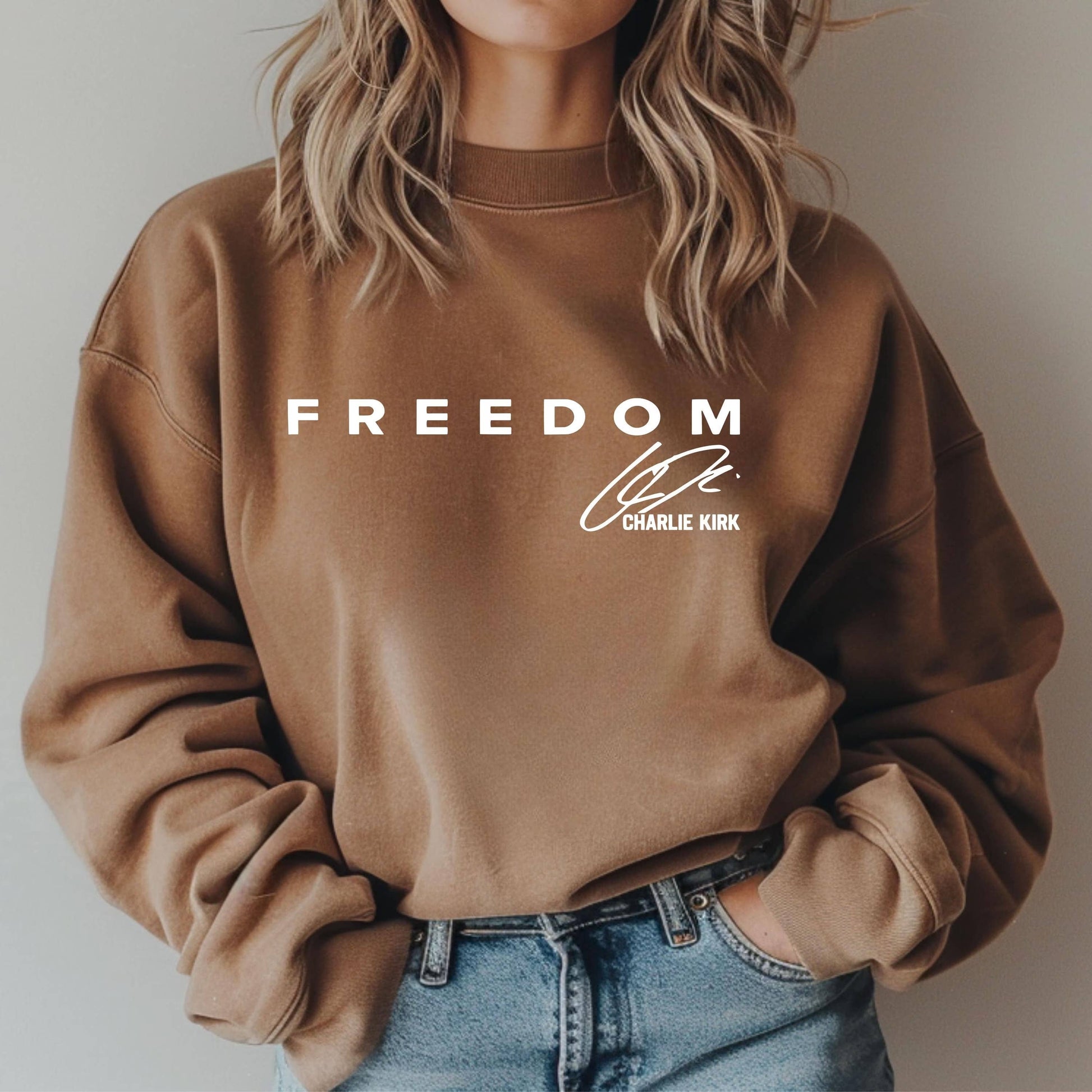 Brown sweatshirt with 'FREEDOM' and 'CHARLIE KIRK' text on a plain background
