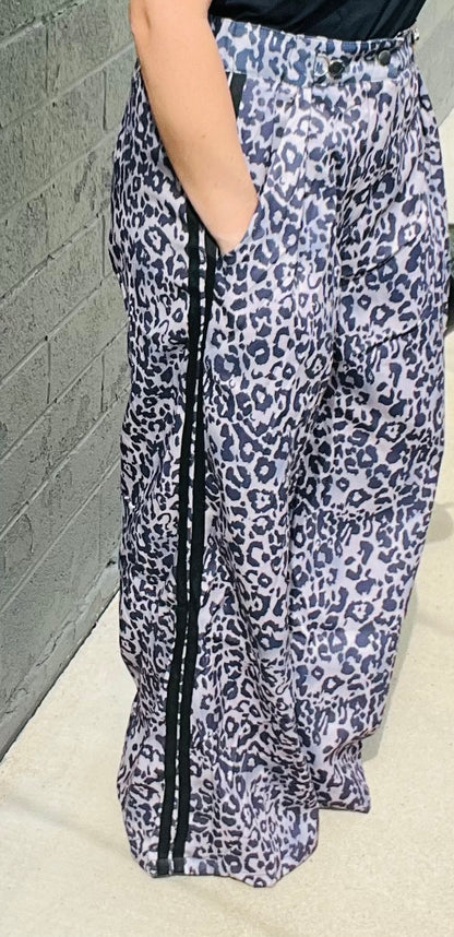 Person wearing leopard print pants against a gray wall.