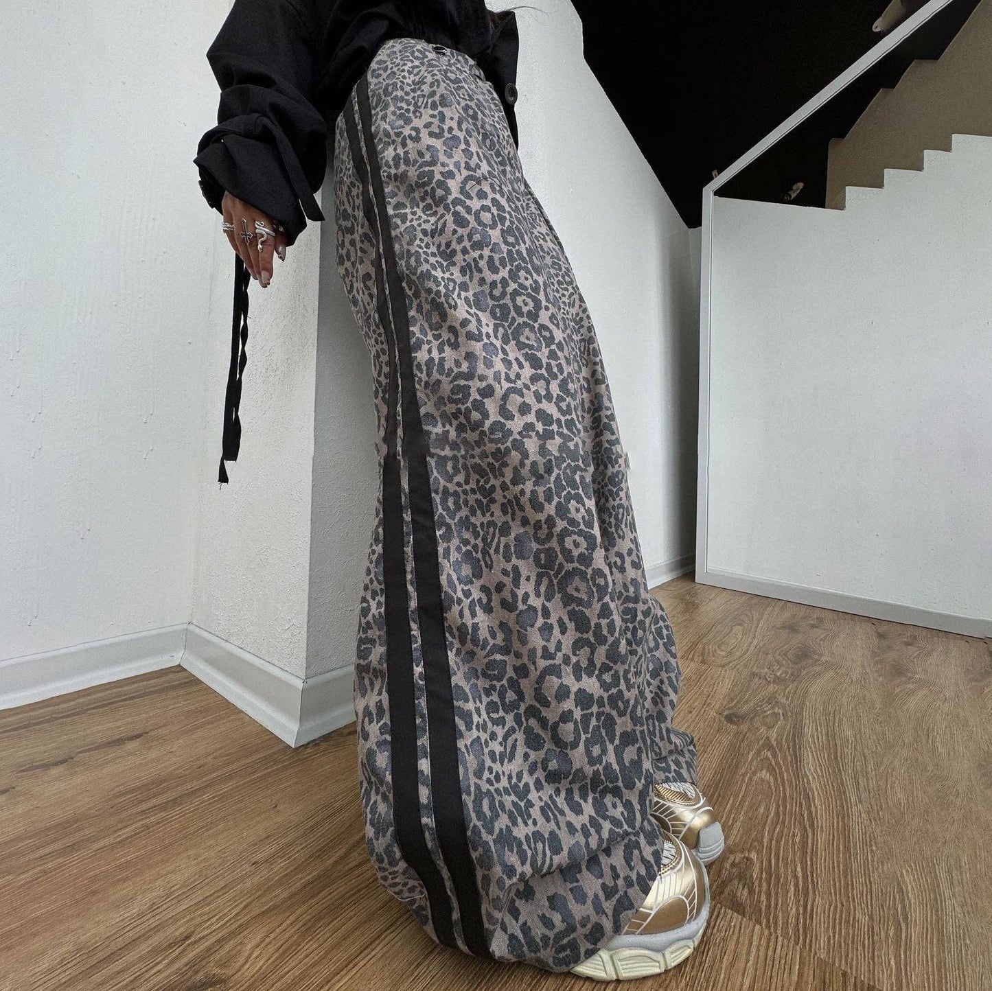 Person wearing leopard print pants and black top in a minimal indoor setting