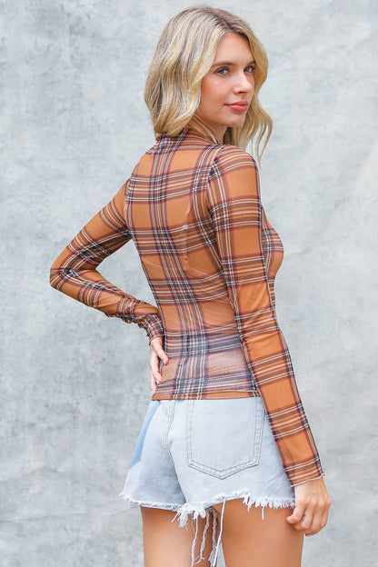 Woman wearing a plaid shirt and denim shorts against a gray background