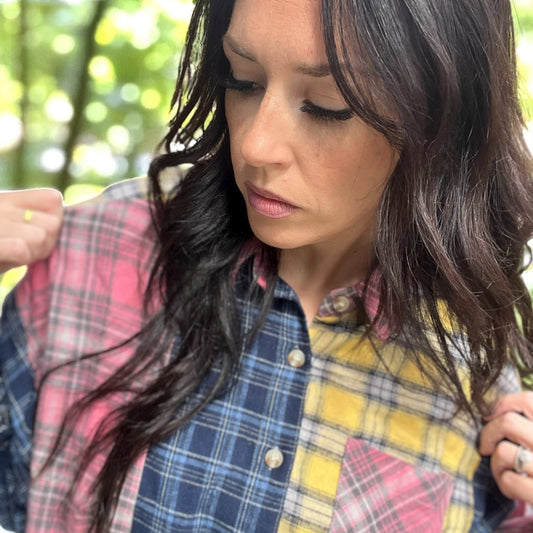 Woman wearing a colorful plaid shirt with a blurred green background