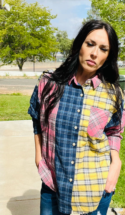 Woman wearing a patchwork plaid shirt outdoors with trees and grass in the background