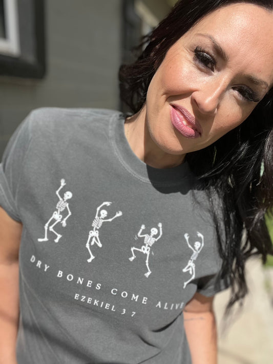 Woman wearing a gray t-shirt with skeleton designs and text.