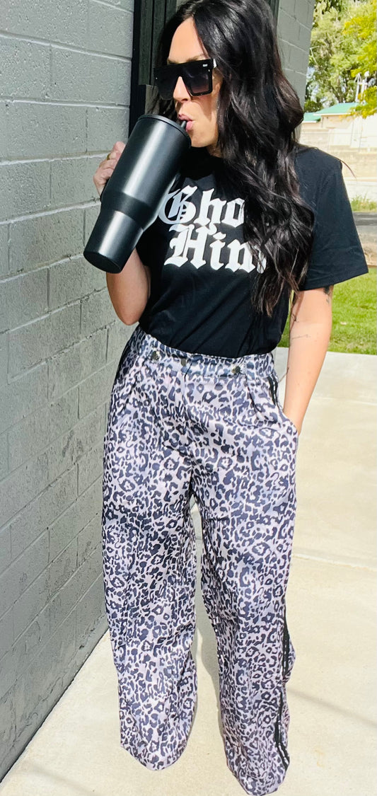 Woman wearing a black t-shirt with 'Ghost Him' text and patterned pants, holding a black tumbler.
