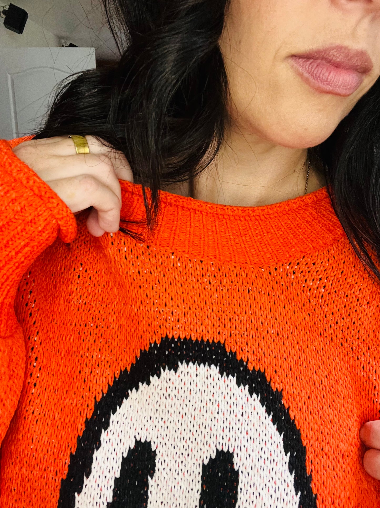 Person wearing an orange sweater with a ghost design