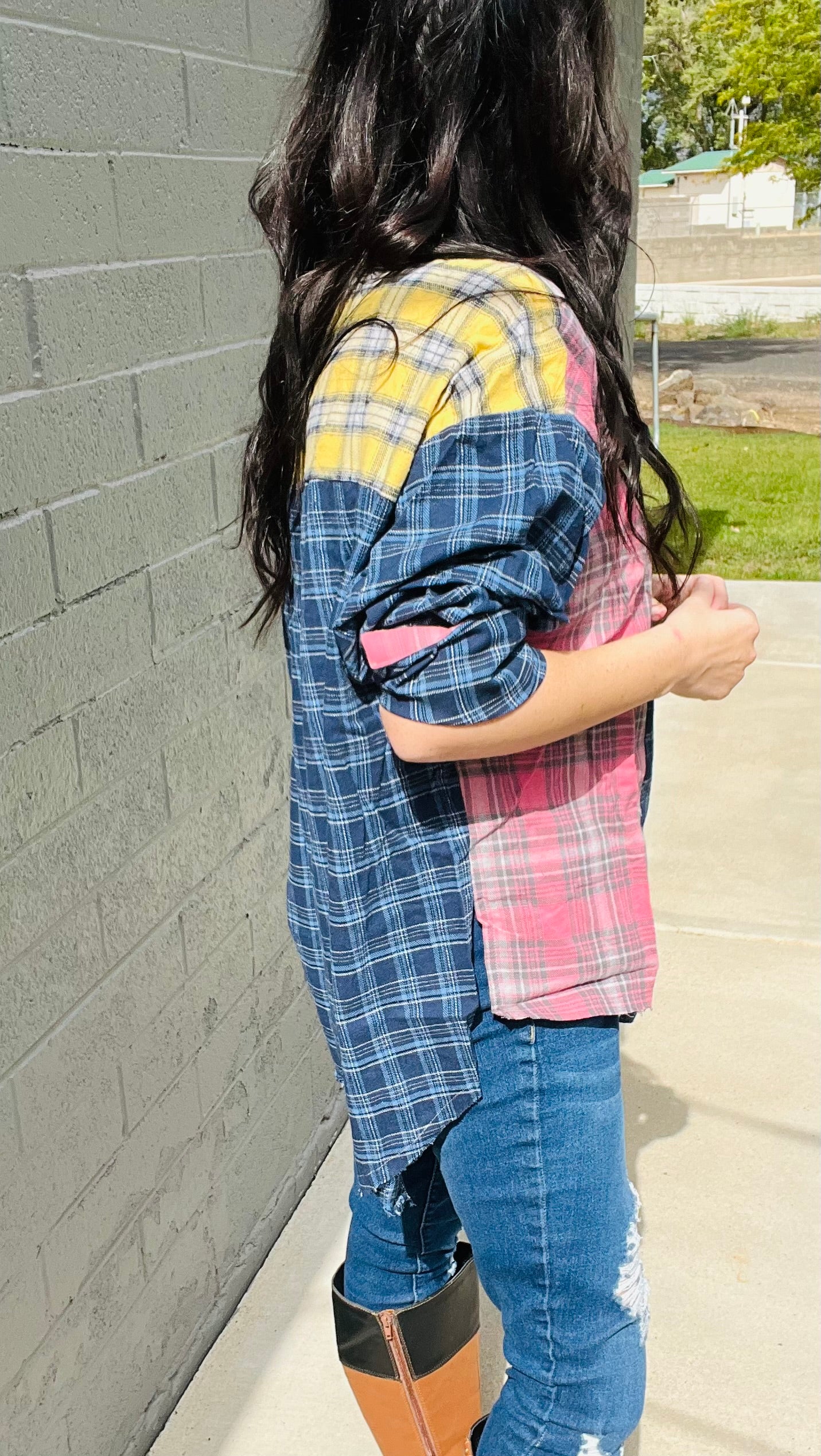 Person wearing a colorful plaid shirt against a gray wall.