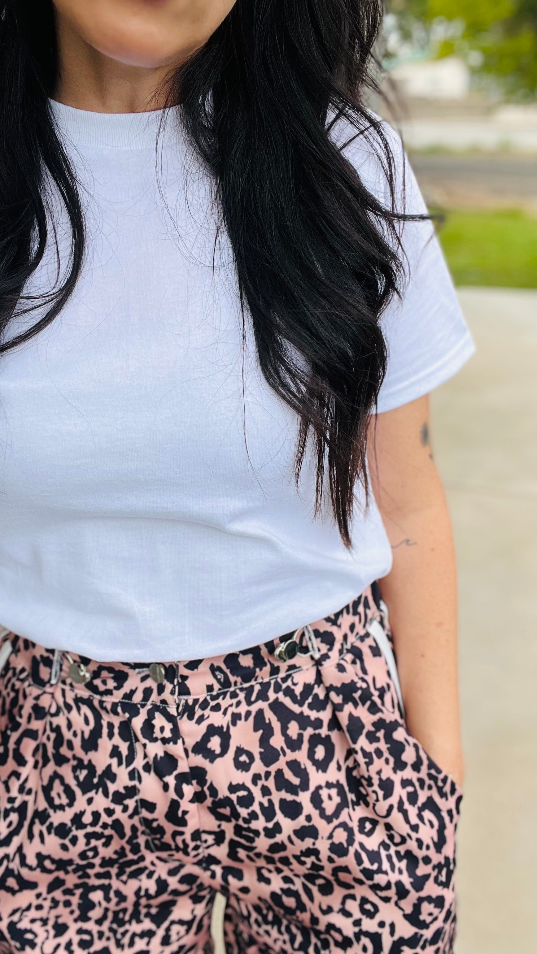 Person wearing a white t-shirt and leopard print pants outdoors