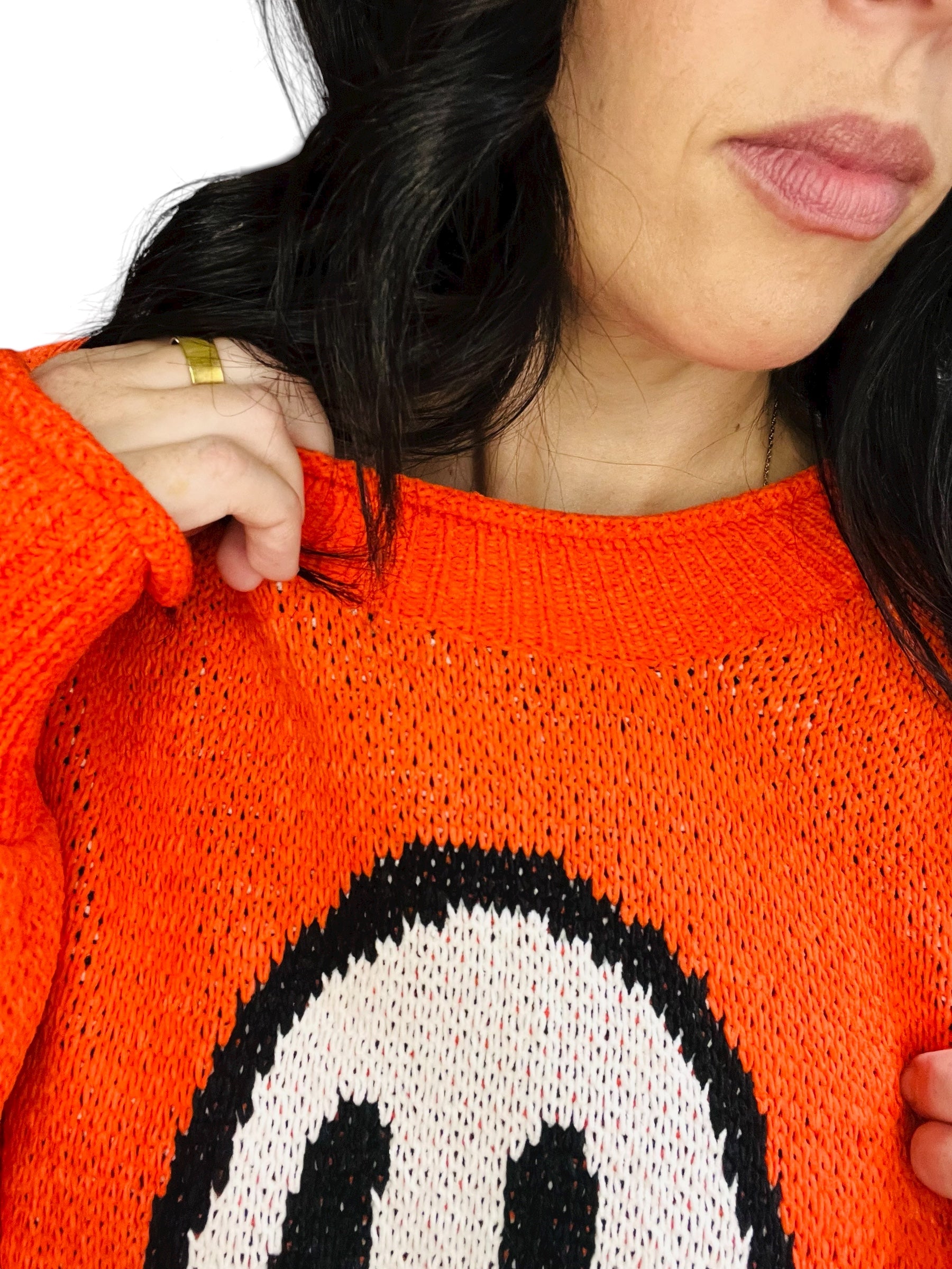 Person wearing an orange sweater with a ghost design